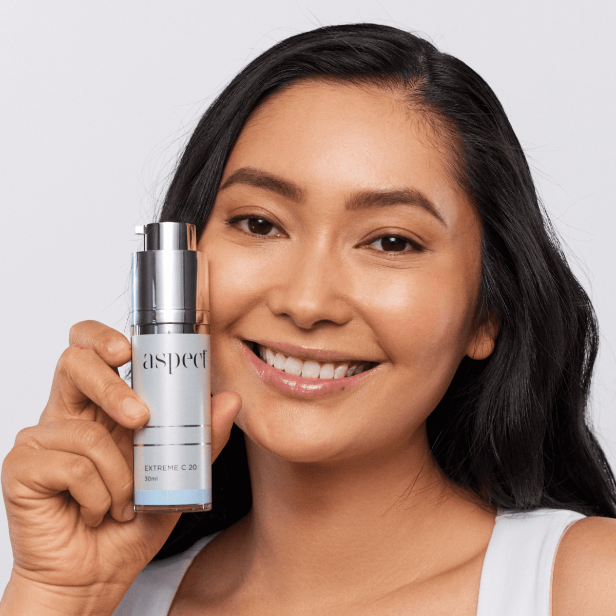 Woman holding Aspect Extreme C 20 serum, highlighting the brightening, firming and collagen-supporting vitamin C formula for radiant, youthful skin.