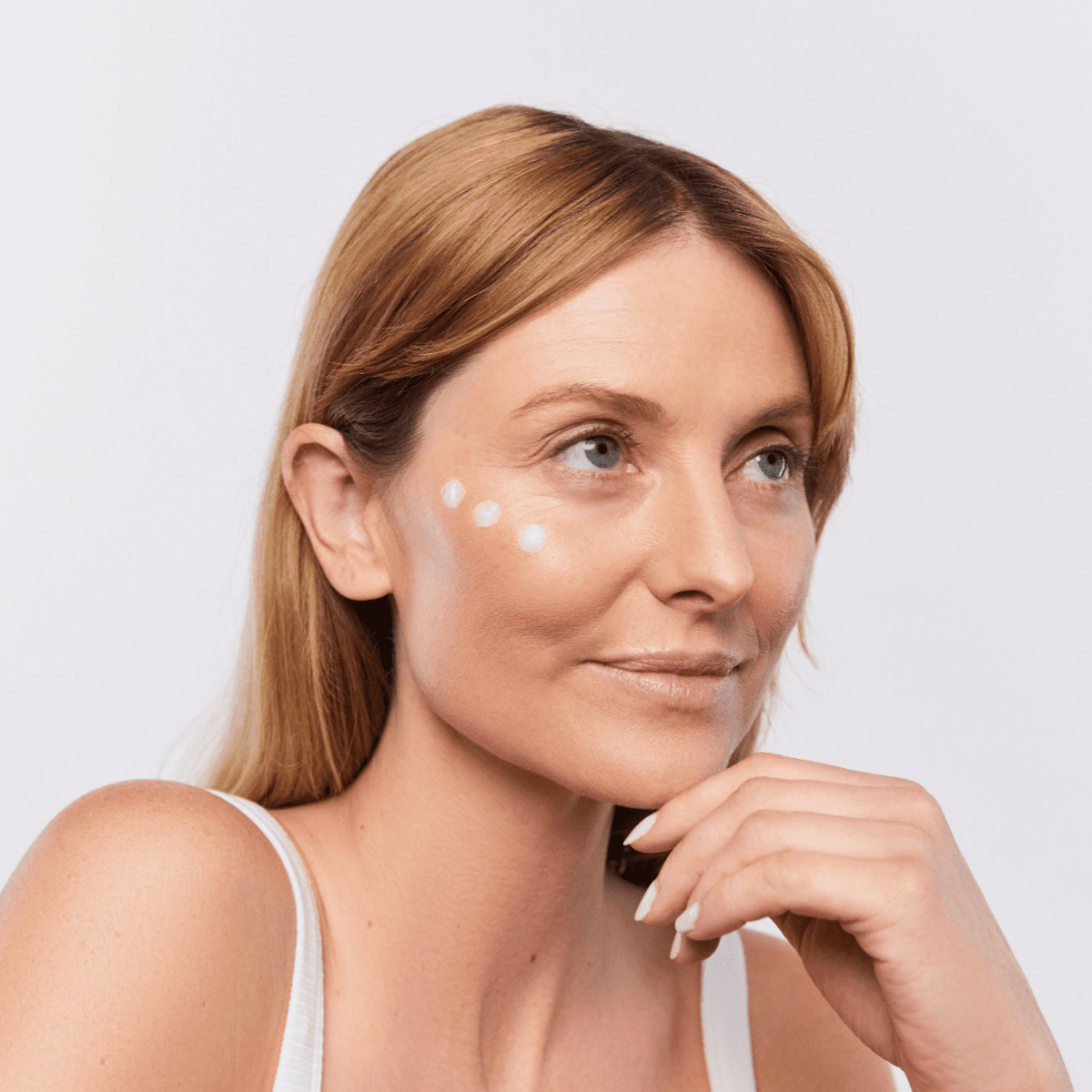 Woman applying Aspect Eyelift 3 under her eyes, demonstrating the creamy peptide-infused texture that targets puffiness, dark circles and fine lines.
