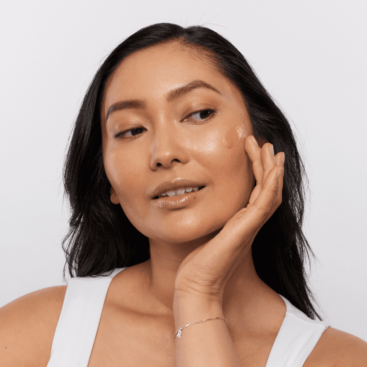 Woman applying Aspect Jungle Brew serum to her face, demonstrating the lightweight, clarifying formula designed to reduce oil, calm redness and refine pores.