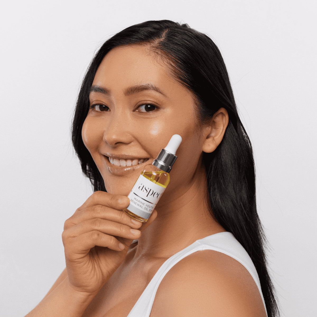Woman holding Aspect Marine Youth Renewal Oil, showcasing the nourishing, antioxidant-rich formula designed to hydrate, firm and boost radiance.