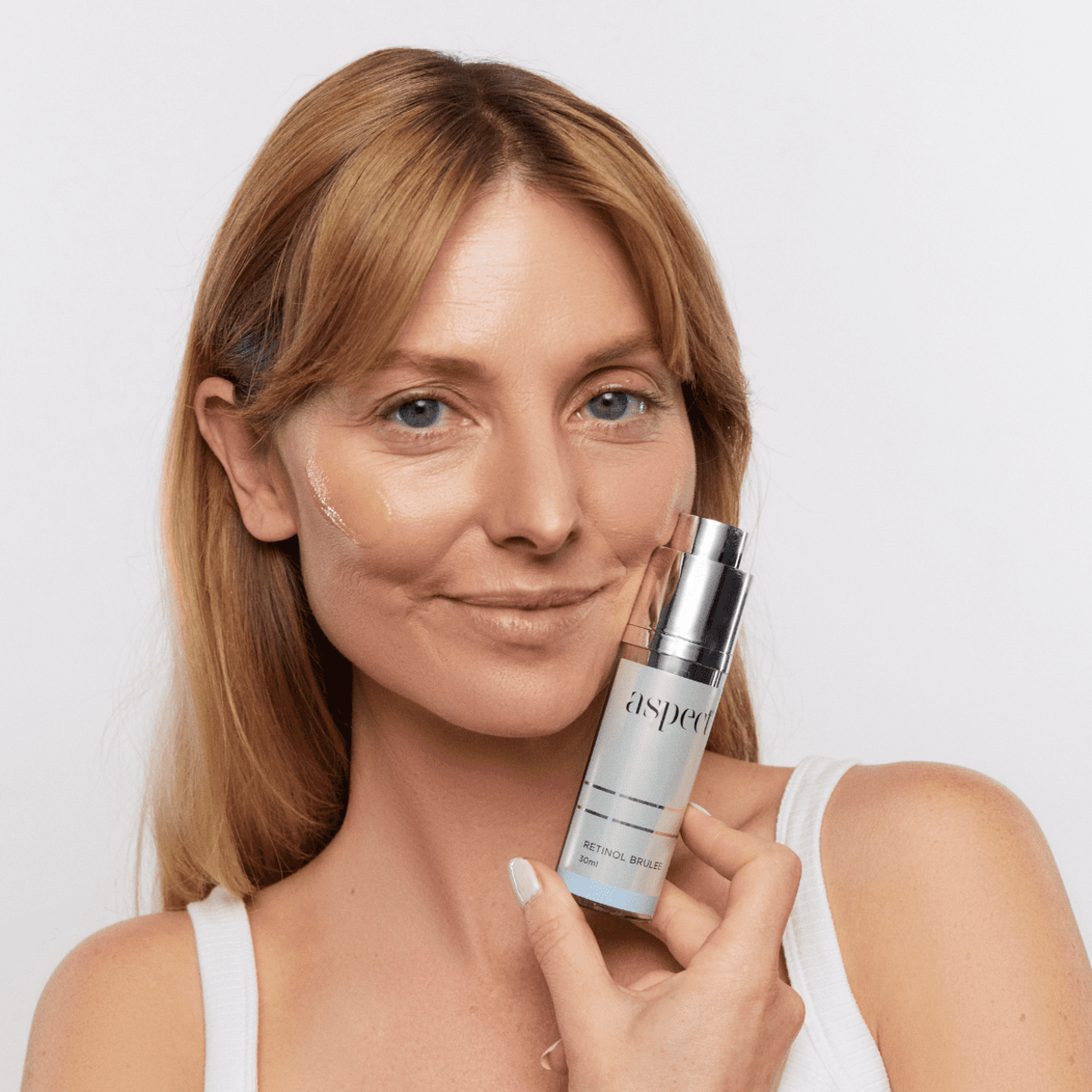 Woman applying Aspect Retinol Brulee to her skin, demonstrating the lightweight retinol texture that renews, smooths and revitalises the complexion overnight.