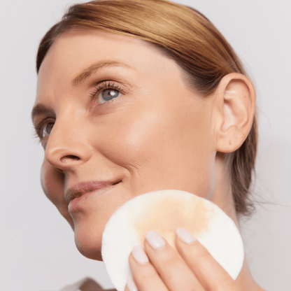 Woman using Aspect Cleansing Micellar Water on a cotton pad to remove makeup, demonstrating the gentle, no-rinse micellar cleansing action.