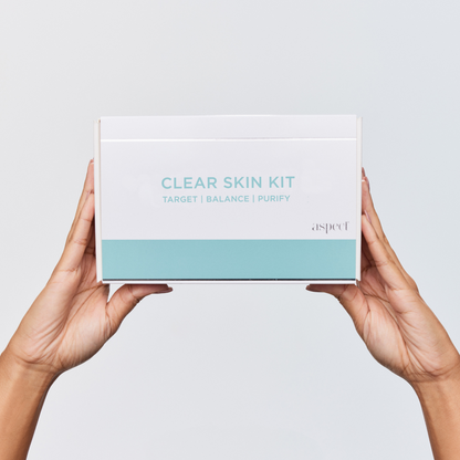 Aspect Clear Skin Kit box held by two hands, showcasing the complete clarifying skincare system for problematic and acne-prone skin.