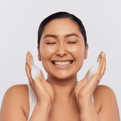 Woman cleansing her face with Aspect Exfoliating Cleanser, demonstrating its purifying, exfoliating action for clearer, smoother, radiant skin.
