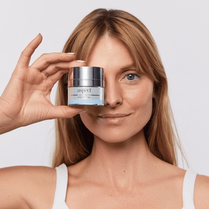 Woman holding Aspect Eyelift 3 eye cream, highlighting the lightweight peptide formula used to firm, hydrate and refresh tired under-eyes.