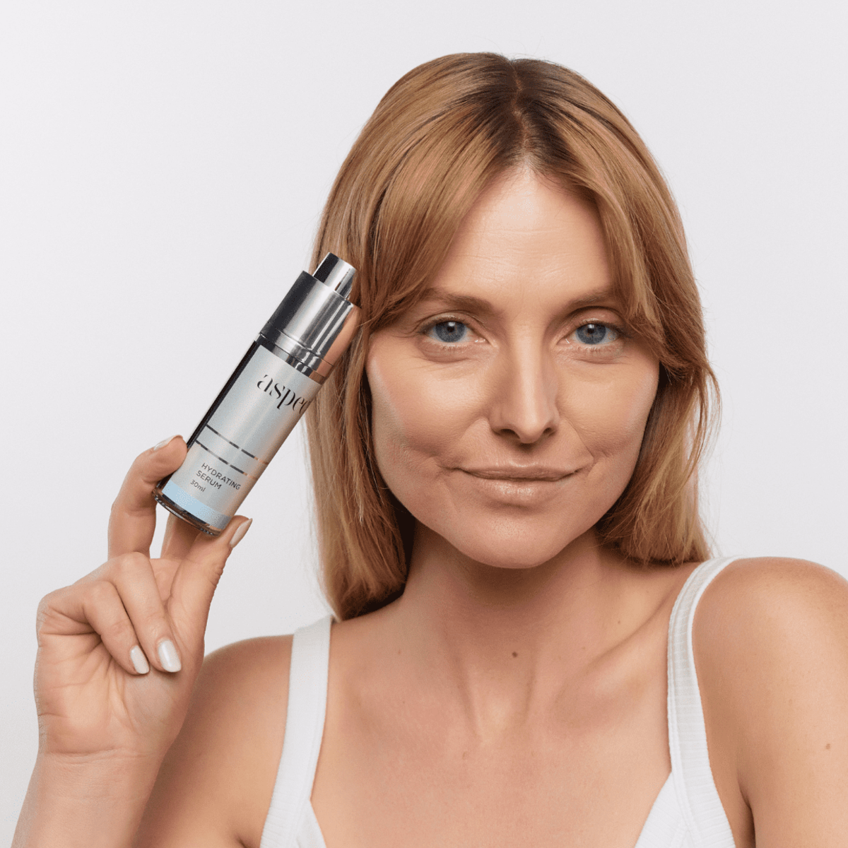 Woman holding Aspect Hydrating Serum with the lid removed, highlighting the lightweight hydrating formula designed to boost moisture and relieve skin dehydration.