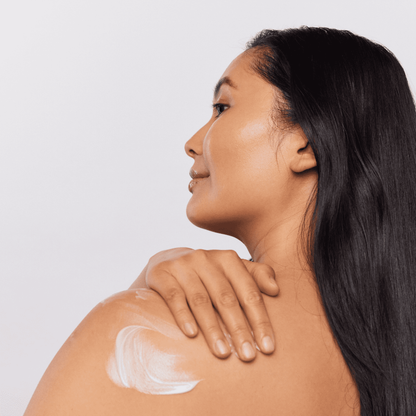 Woman applying Aspect Luxe Body Cream to her bare shoulder, demonstrating the rich, smoothing formula that hydrates, softens and rejuvenates dry skin.