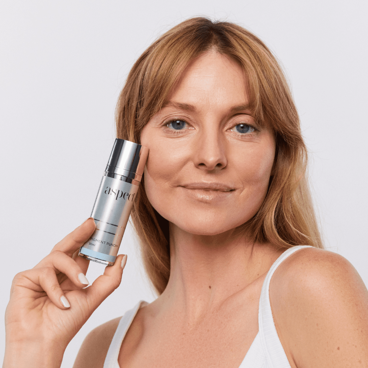 Woman holding Aspect Pigment Punch+ brightening serum, highlighting its powerful formula for reducing pigmentation and improving overall skin clarity.