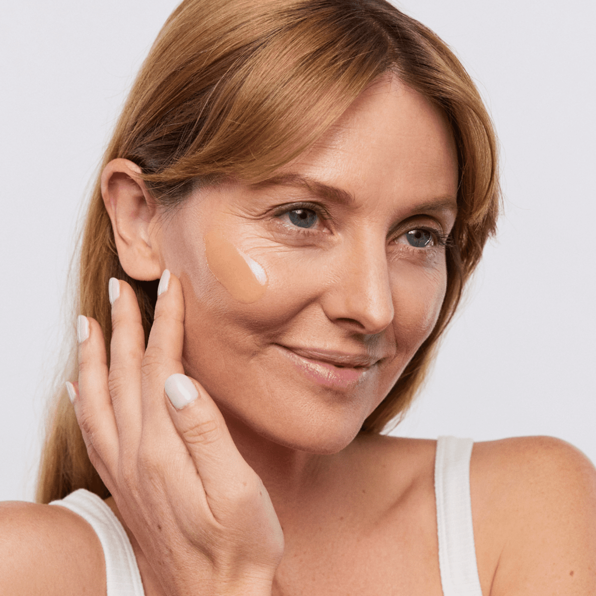 Woman applying Aspect Pigment Punch+ serum to her face, demonstrating the lightweight brightening formula designed to fade dark spots and even skin tone.