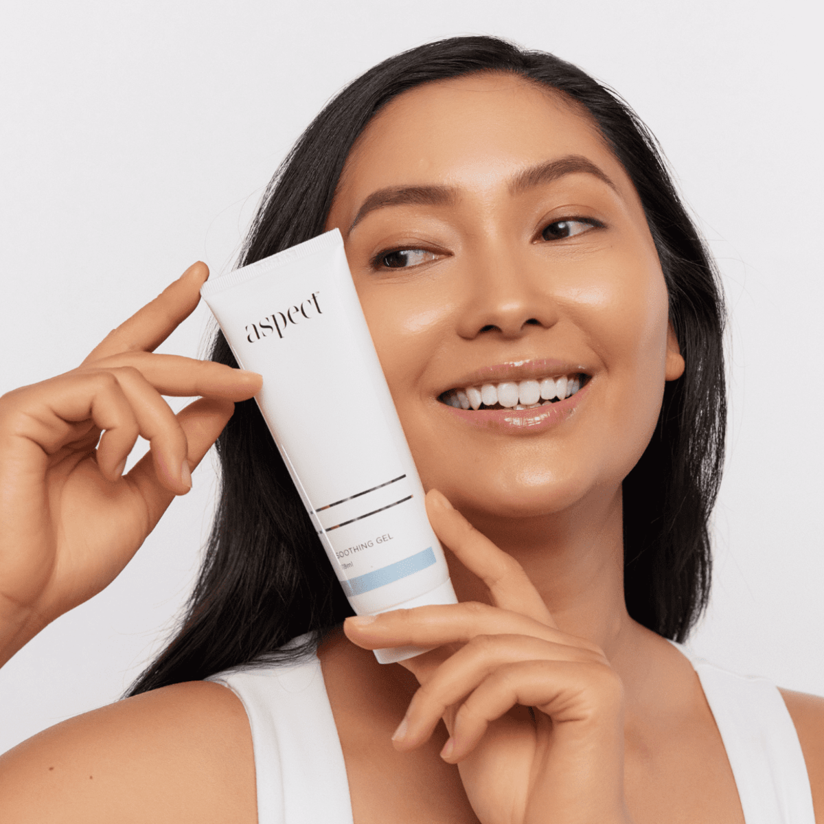 Woman holding Aspect Soothing Gel, highlighting the cooling aloe-based formula that relieves redness, hydrates and comforts sensitive skin.
