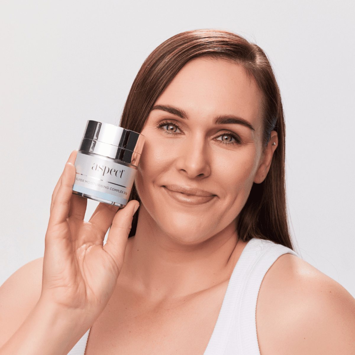 Woman holding Aspect Super Moisturising Complex, highlighting the rich, nourishing cream designed to hydrate, smooth and rejuvenate dry, dehydrated or mature skin.