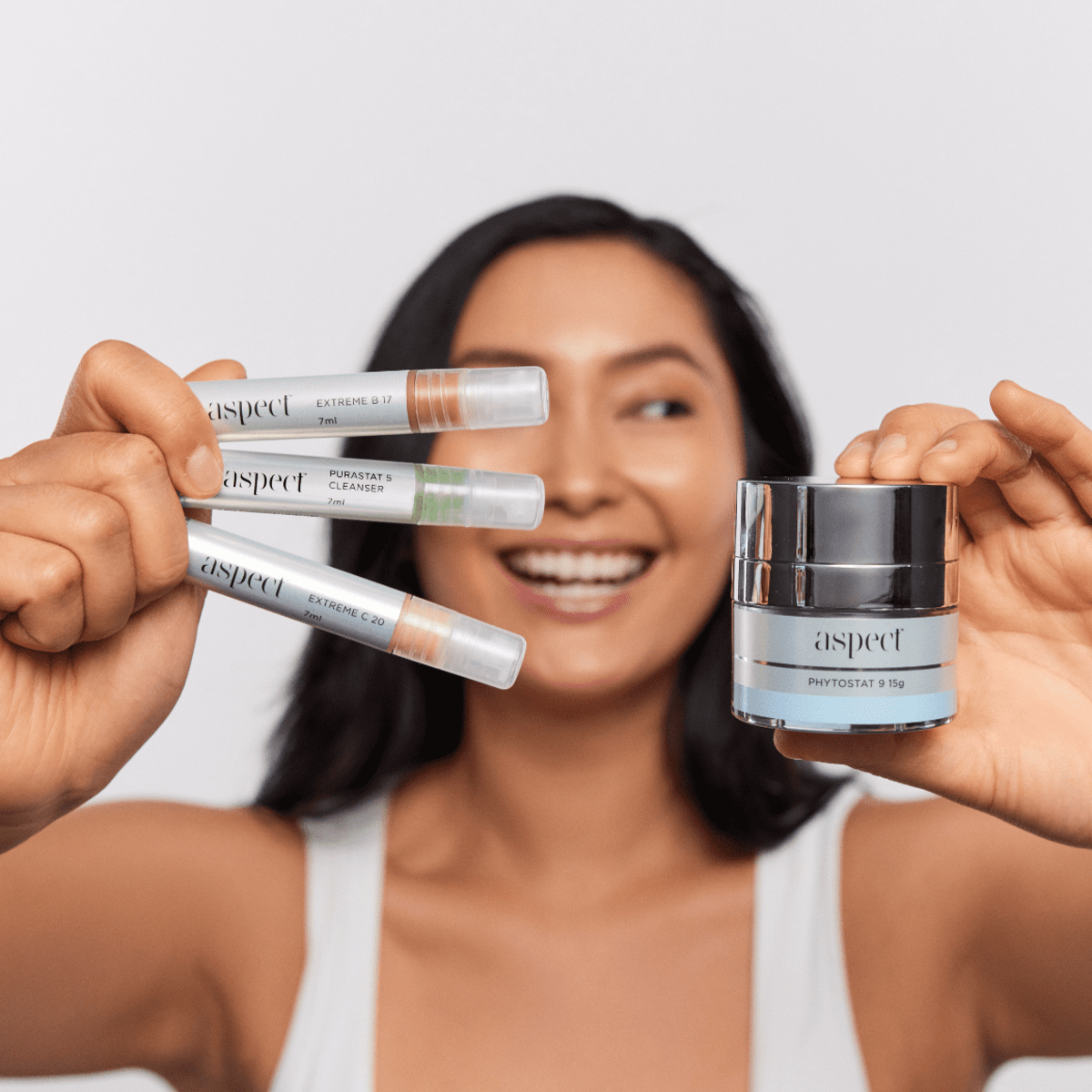 Woman holding the Aspect Try Me Kit minis, highlighting the travel-friendly cleanser, serum and moisturiser set designed to brighten, hydrate and nourish skin.