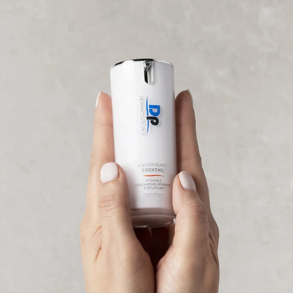 Dp Dermaceuticals Antioxidant Cocktail 15ml held in hand, a lightweight antioxidant serum for brighter-looking skin and daily environmental defence.
