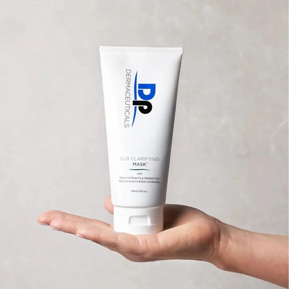 Hand holding Dp Dermaceuticals CLR Clarifying Mask against a grey background, showcasing product size and professional cosmeceutical packaging.