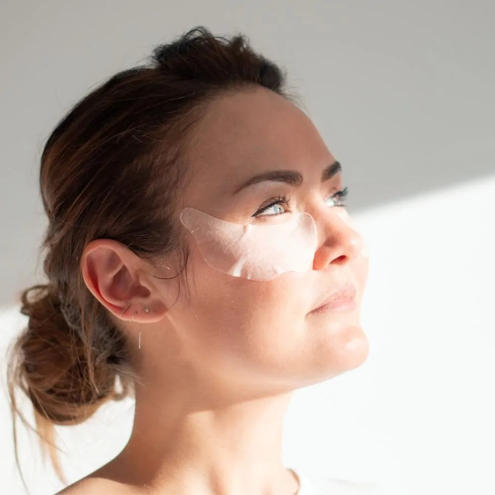 Woman with Dp Dermaceuticals Rapid Eye Restore Masks applied under the eyes, showing fit, contour and hydrating treatment in use.