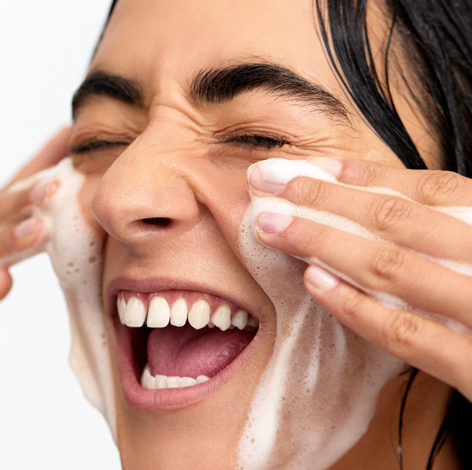 Woman cleansing face with INSKIN.CO Foaming Enzyme Cleanser showing rich creaming foam texture and gentle enzyme exfoliation.