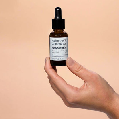 Mesoestetic Melan Tran3x Concentrate held in hand, a depigmenting serum designed to visibly reduce dark spots and correct uneven pigmentation.