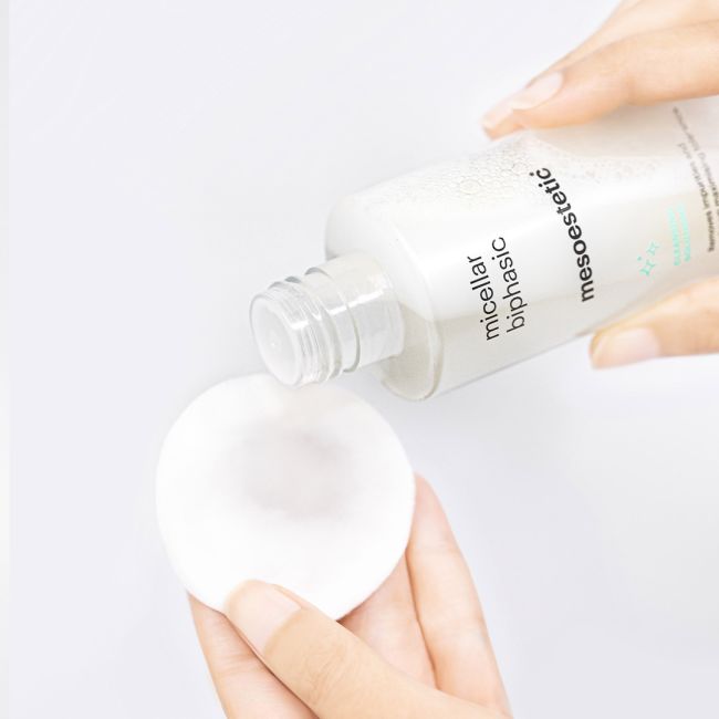 Mesoestetic Micellar Biphasic being applied to a cotton pad, a gentle dual-phase cleanser for eyes and lips that removes makeup and impurities with minimal irritation.