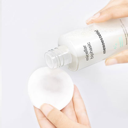 Mesoestetic Micellar Biphasic being applied to a cotton pad, a gentle dual-phase cleanser for eyes and lips that removes makeup and impurities with minimal irritation.
