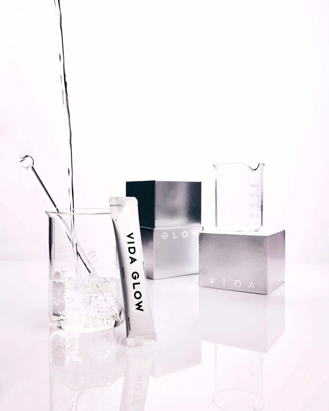 Vida Glow Pro Collagen+ collagen powder supplement for skin hydration and elasticity, styled with water and glassware to reflect easy daily mixing.